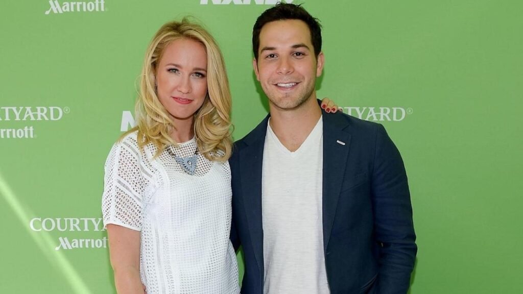 A man and woman stand together, smiling, in a scene from "Anna Camp’s New Love Story